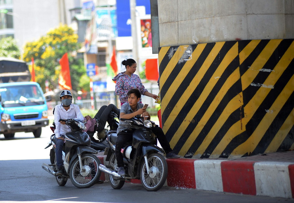  Người dân tại Hà Nội tranh thủ nghỉ ngơi dưới những gốc cây, gầm cầu vượt để tránh nắng nóng. (Ảnh: Quang Quyết/TTXVN) 