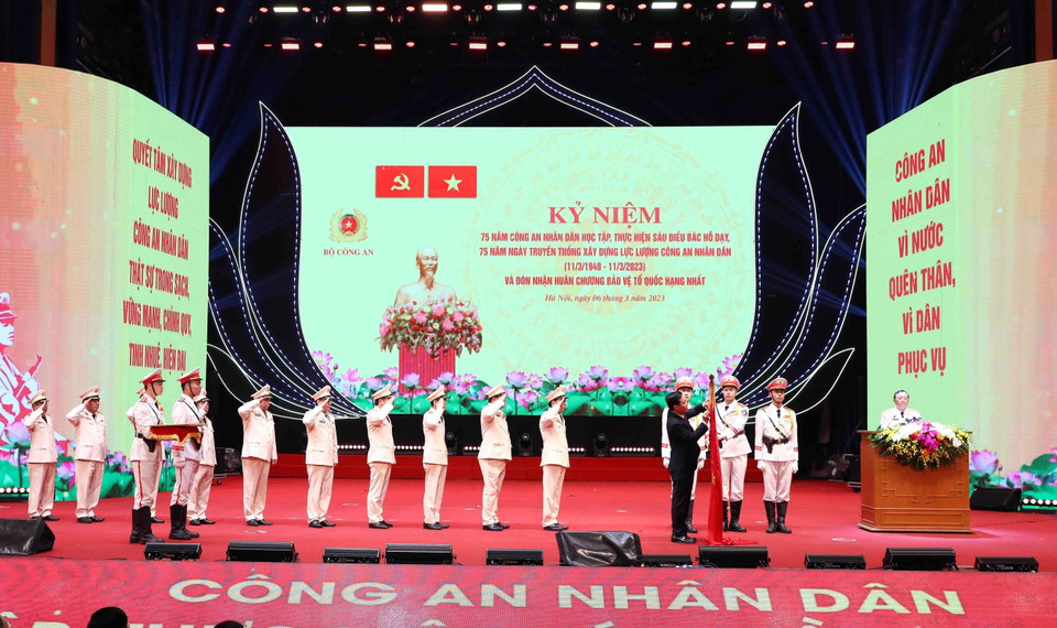 Chủ tịch nước Võ Văn Thưởng gắn Huân chương Bảo vệ Tổ quốc hạng Nhất lên lá cờ truyền thống Xây dựng lực lượng công an nhân dân. (Ảnh: Phạm Kiên/TTXVN)