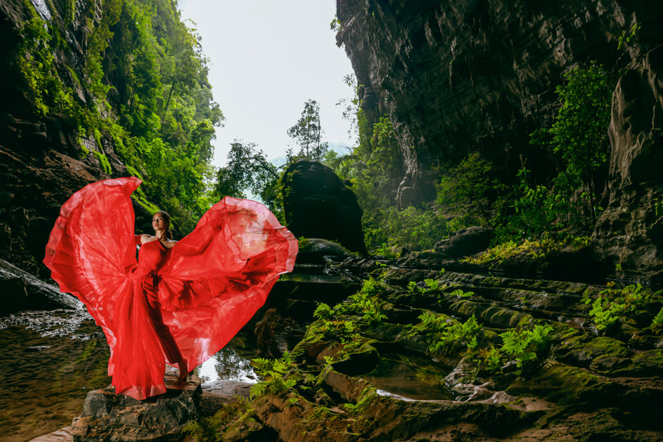 Hình ảnh Hoàng My trong sắc đỏ rực rỡ của chiếc váy ở giữa lòng hang Tiên giống một bông hoa đang khoe sắc. (Nguồn ảnh: Vietnam+)