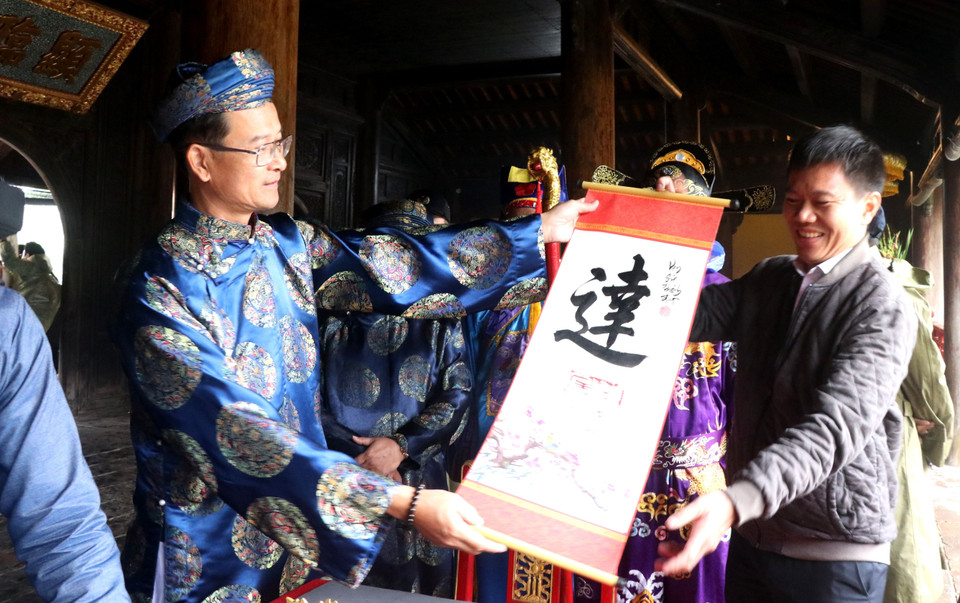 Lãnh đạo Trung tâm Bảo tồn Di tích Cố đô Huế tặng chữ cho du khách. (Ảnh: Tường Vi/TTXVN)