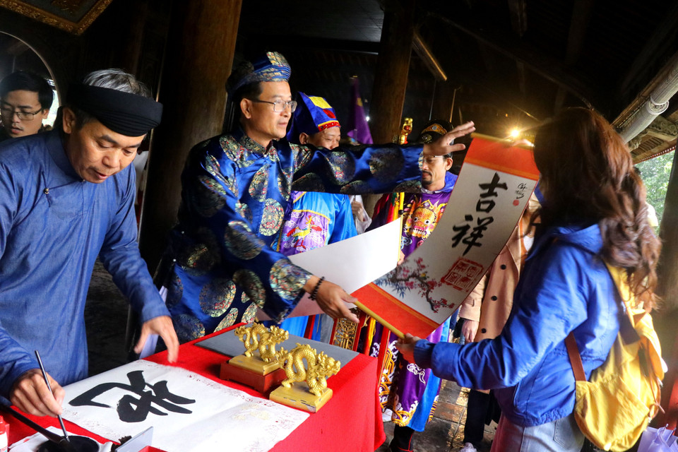 Lãnh đạo Trung tâm Bảo tồn Di tích Cố đô Huế tặng chữ cho du khách. (Ảnh: Tường Vi/TTXVN)