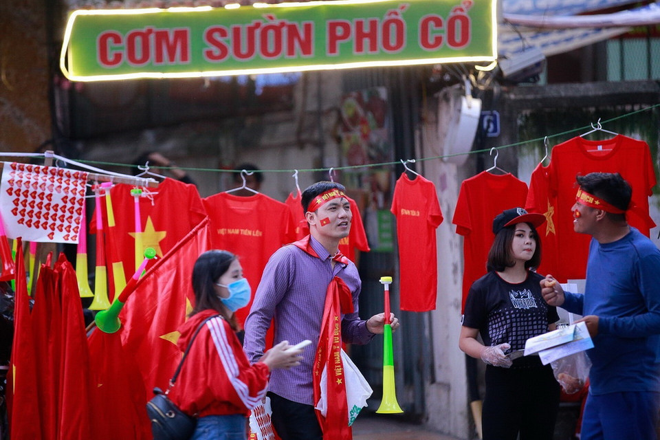 Rất nhiều cờ đỏ sao vàng, áo, băng rôn in chữ 'Việt Nam chiến thắng' được bán trên phố Trịnh Hoài Đức phục vụ người hâm mộ. (Ảnh: Trọng Đạt/TTXVN)