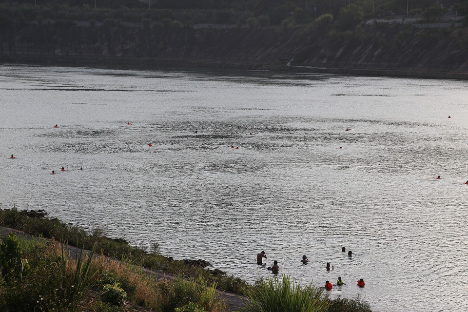 Người lớn lẫn trẻ em xuống tắm sông Đà trong những ngày nắng nóng, mặc cho việc cảnh báo nguy hiểm và những hệ lụy đã xuất hiện trong những năm trước. (Ảnh: Trọng Đạt/TTXVN)