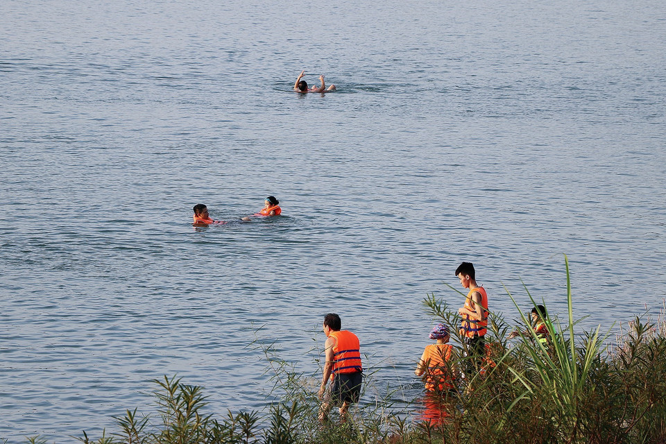 Người lớn lẫn trẻ em xuống tắm sông Đà trong những ngày nắng nóng, phớt lờ những biển cấm, cảnh báo nguy hiểm. (Ảnh: Trọng Đạt/TTXVN)