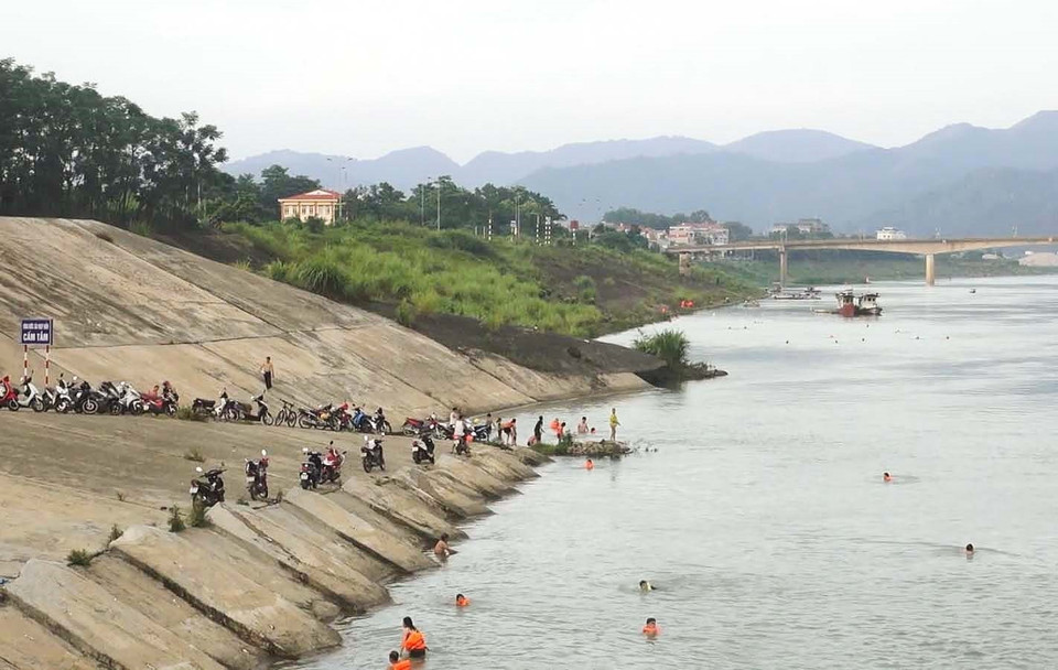 Người dân dựng xe la liệt bên bờ sông Đà để xuống tắm sông, phớt lờ cảnh báo nguy hiểm. (Ảnh: Trọng Đạt/TTXVN)