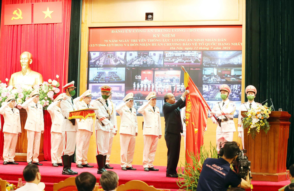 Chủ tịch nước Nguyễn Xuân Phúc gắn Huân chương Bảo vệ Tổ quốc hạng Nhất lên lá cờ truyền thống của lực lượng an ninh nhân dân. (Ảnh: Phạm Kiên/TTXVN)