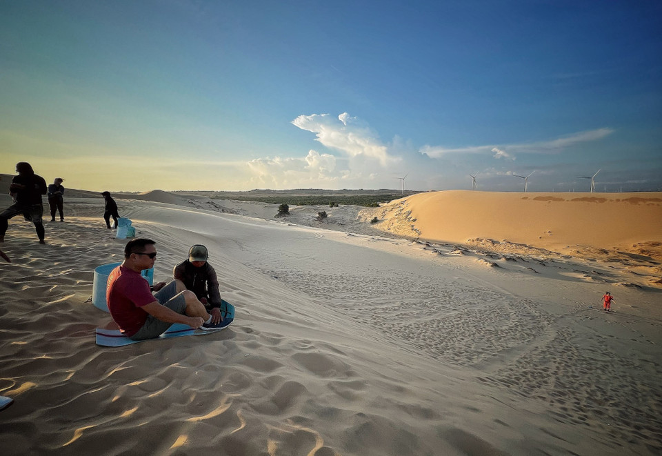 Đến Bàu Trắng du khách có thể thử cảm giác mạnh với trò trượt cát. (Ảnh: Mai Mai/Vietnam+)
