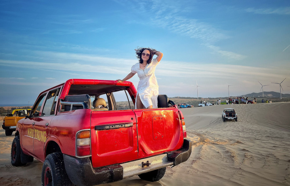 Nguyễn Minh Thu, du khách từ Hà Nội cho biết cô thực sự ấn tượng trước vẻ đẹp hoàng hôn của Bàu Trắng và tranh thủ tạo dáng trước khi Mặt Trời rực đỏ buông xuống những đụn cát khổng lồ. (Ảnh: Mai Mai/Vietnam+)