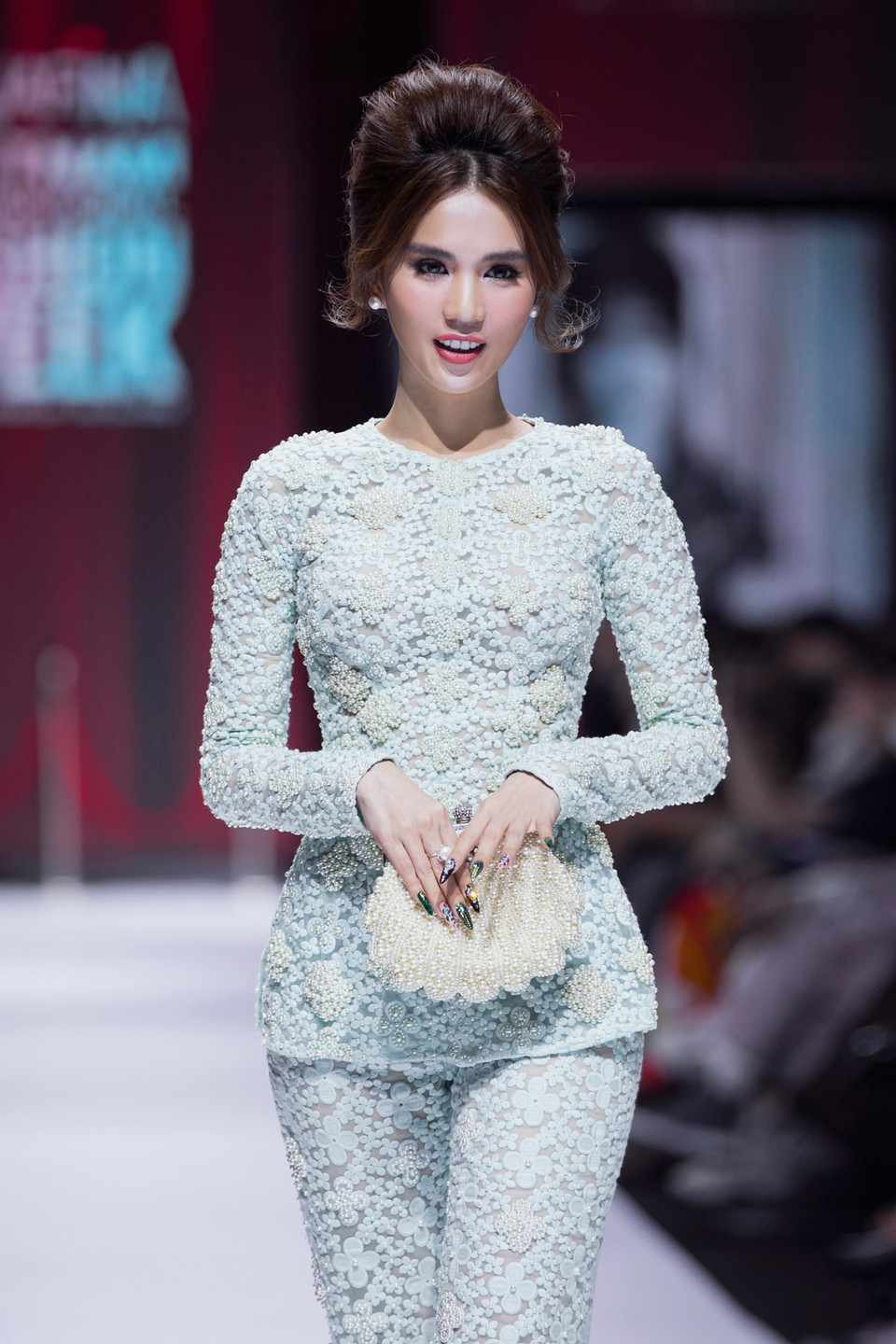 'Nữ hoàng nội y' Ngọc Trinh hóa thành quý cô thanh lịch với mái tóc bới cao trình diễn bộ trang phục với quần ống loe và áo dài tay màu xanh ngọc thay vì áo dài. (Ảnh: CTV/Vietnam+)