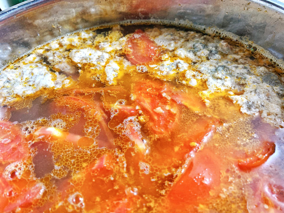 Cua mua về lột yếm và mai, khêu gạch xong thì đem xay hoặc giã tay. Cua vừa giã cho vào bát nước, dùng tay bóp nhẹ cho thịt cua tan đều vào nước rồi lọc lại bỏ bã, làm 2-3 lần để lọc hết cặn. Cho thêm chút muối ăn, đường, hạt nêm và nước cua này rồi cho vào nồi, bắc lên bếp đun lửa vừa. Khi đun khuấy nhẹ cho cua kết lại với nhau thì vớt phần thịt cua ra bát riêng. Cà chua xào sơ rồi cho vào nồi nước cua. Thêm chút mắm tôm cho vừa miệng và đun tiếp. (Ảnh: Mai Mai/Vietnam+)