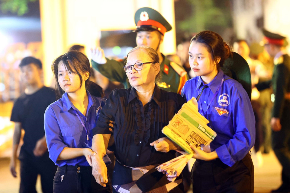 Một người dân được lực lượng thanh niên hỗ trợ đưa vào viếng Tổng Bí thư. (Ảnh: TTXVN)