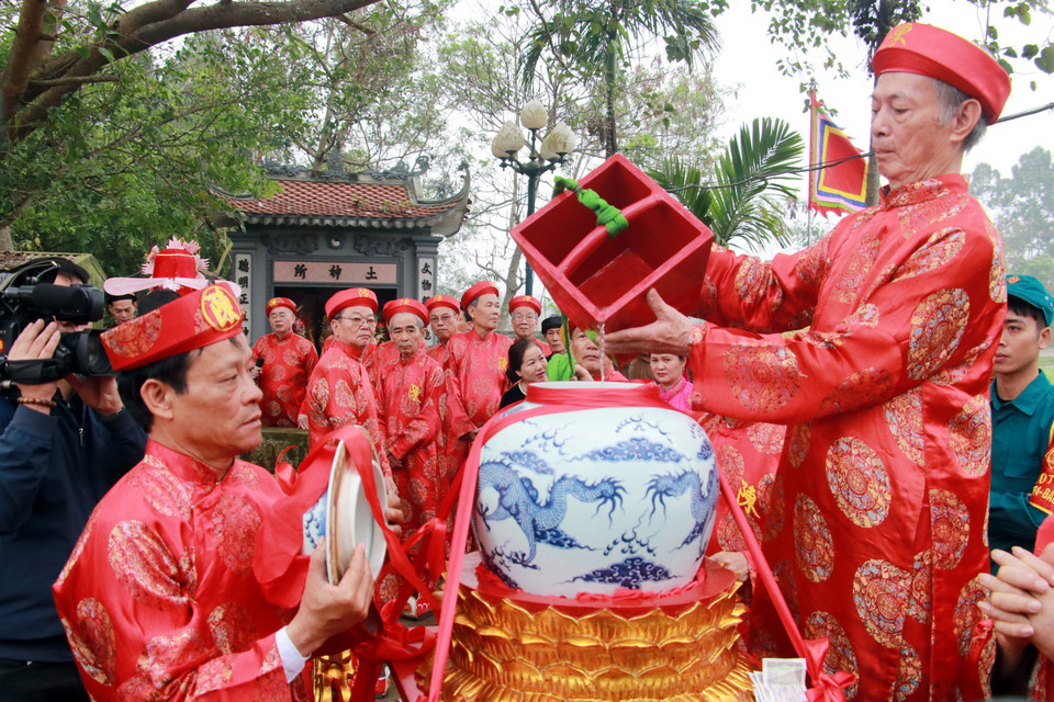 Các cụ cao niên thực hiện nghi thức lấy nước từ giếng rồng. (Ảnh: Nguyễn Lành/TTXVN)