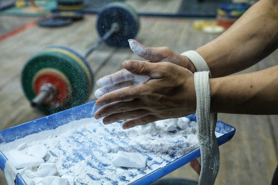 Trước khi nâng tạ, các đô cử thường xoa bột vào tay để chống trơn trượt. (Ảnh: Tuấn Anh/TTXVN)