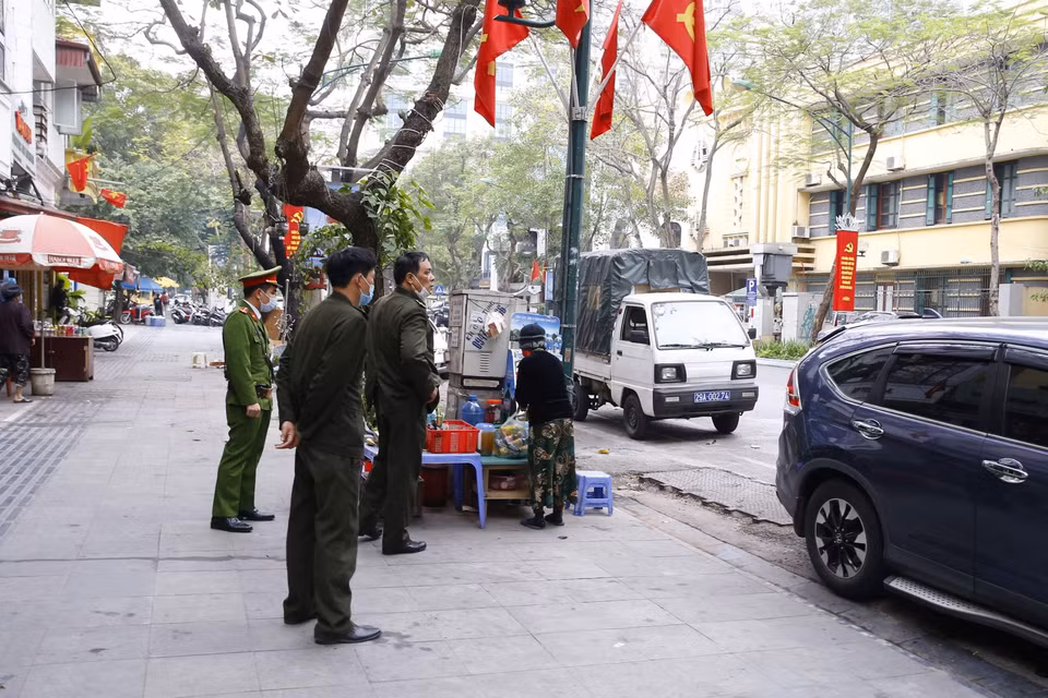 Lực lượng chức năng công an phường Cửa Nam ra quân đề nghị các hộ kinh doanh đóng cửa quán ăn đường phố, trà đá, cà phê. (Ảnh: Doãn Tấn/TTXVN)
