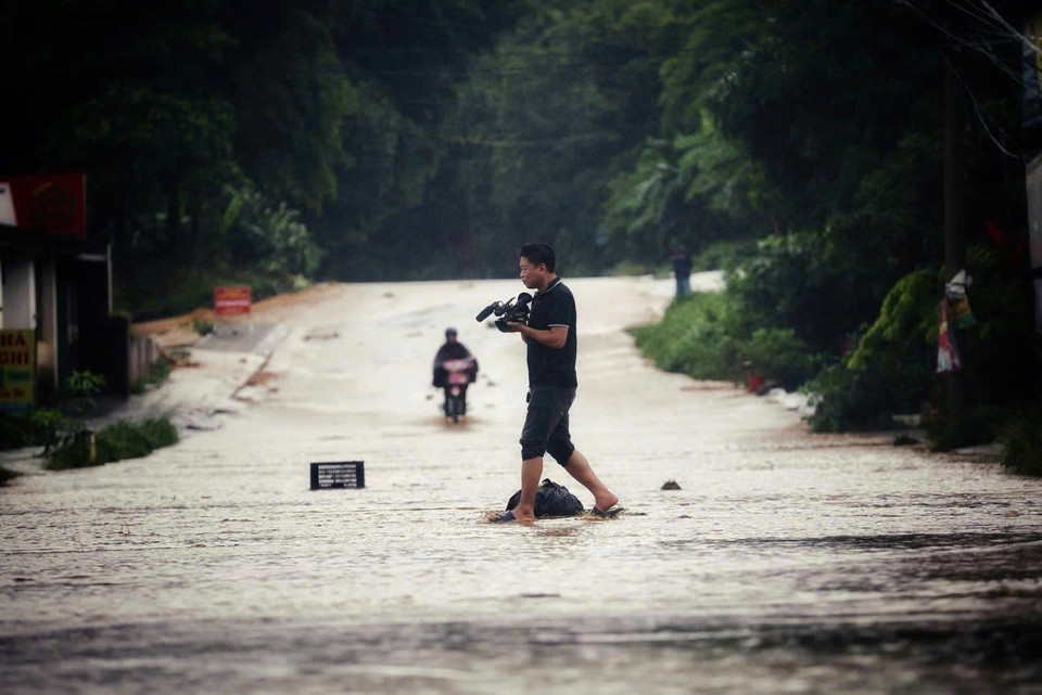 Phóng viên Bùi Thanh Hải, Cơ quan thường trú Hòa Bình, tác nghiệp tại khu vực ngập lụt ngầm Giè, Thành phố Hòa Bình. (Ảnh: TTXVN)