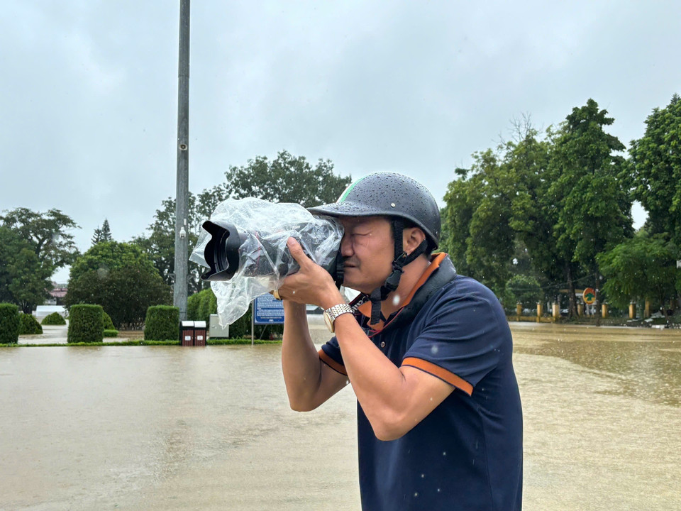Phóng viên Quang Cường, Cơ quan thường trú Tuyên Quang, tác nghiệp mưa lũ tại phường Minh Xuân, TP Tuyên Quang. (Ảnh: TTXVN)