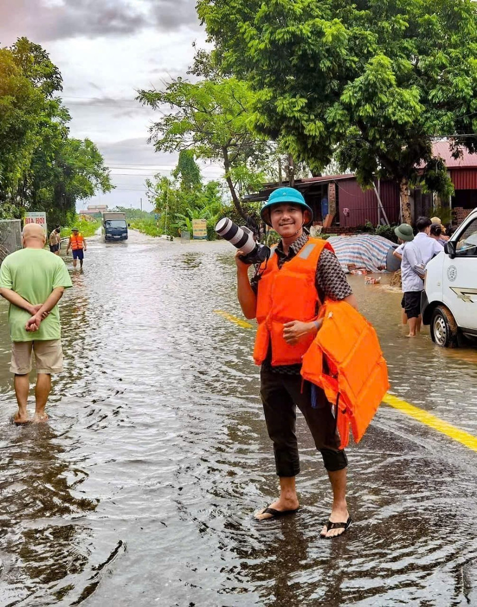 Phóng viên Thanh Tùng, Ban Biên tập Ảnh, tác nghiệp tại vùng ngập lụt xã Trung Giã, huyện Sóc Sơn. (Ảnh: TTXVN)