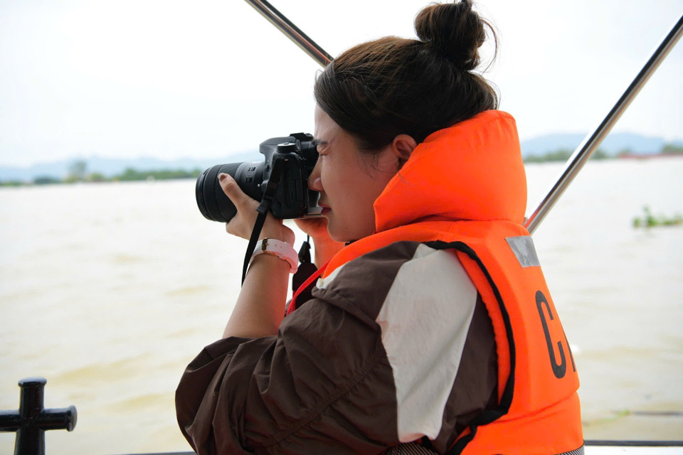 Phóng viên Thuỳ Dung, Cơ quan thường trú Ninh Bình, tác nghiệp tại vùng ngập lụt xã Gia Lạc, huyện Gia Viễn. (Ảnh: TTXVN)