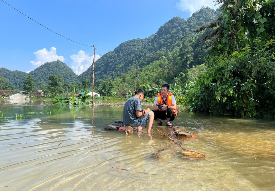 Phóng viên Chu Hiệu, Cơ quan thường trú Cao Bằng, tác nghiệp tại vùng ngập lụt xã Quang Vinh, huyện Trùng Khánh. (Ảnh: TTXVN)