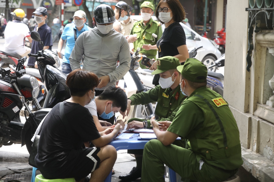 Lực lượng chức năng xử phạt hành chính người không đeo khẩu trang nơi công cộng. (Ảnh: Minh Quyết/TTXVN)