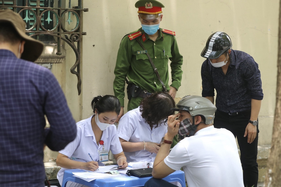 Lực lượng chức năng xử phạt hành chính người không đeo khẩu trang nơi công cộng. (Ảnh: Minh Quyết/TTXVN)