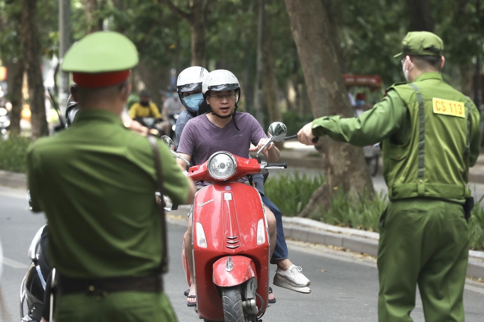 Lực lượng chức năng nhắc nhở, xử lý các trường hợp không đeo khẩu trang nơi công cộng. (Ảnh: Minh Quyết/TTXVN)