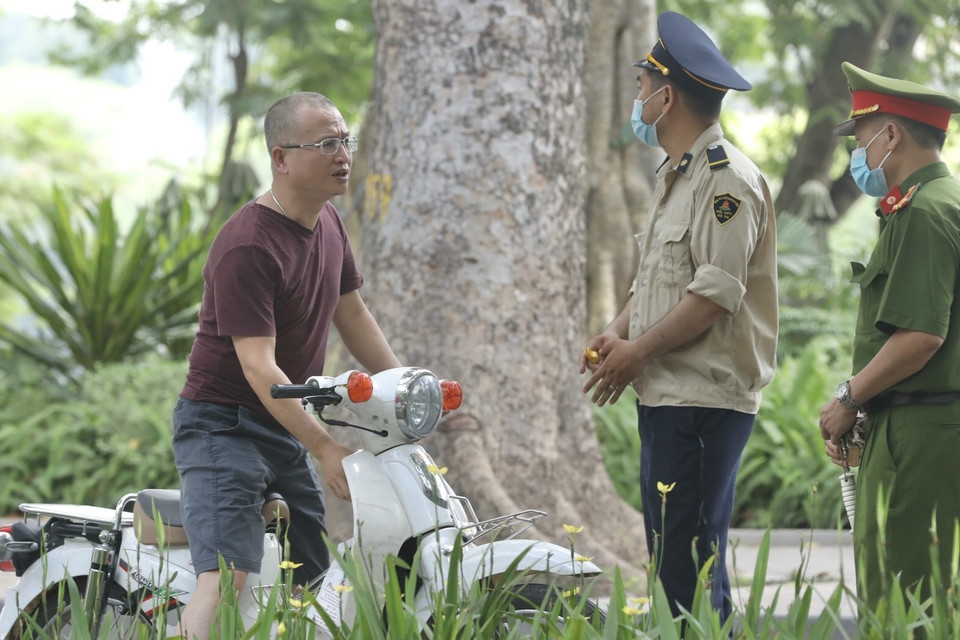 Lực lượng chức năng nhắc nhở, xử lý các trường hợp không đeo khẩu trang nơi công cộng. (Ảnh: Minh Quyết/TTXVN)