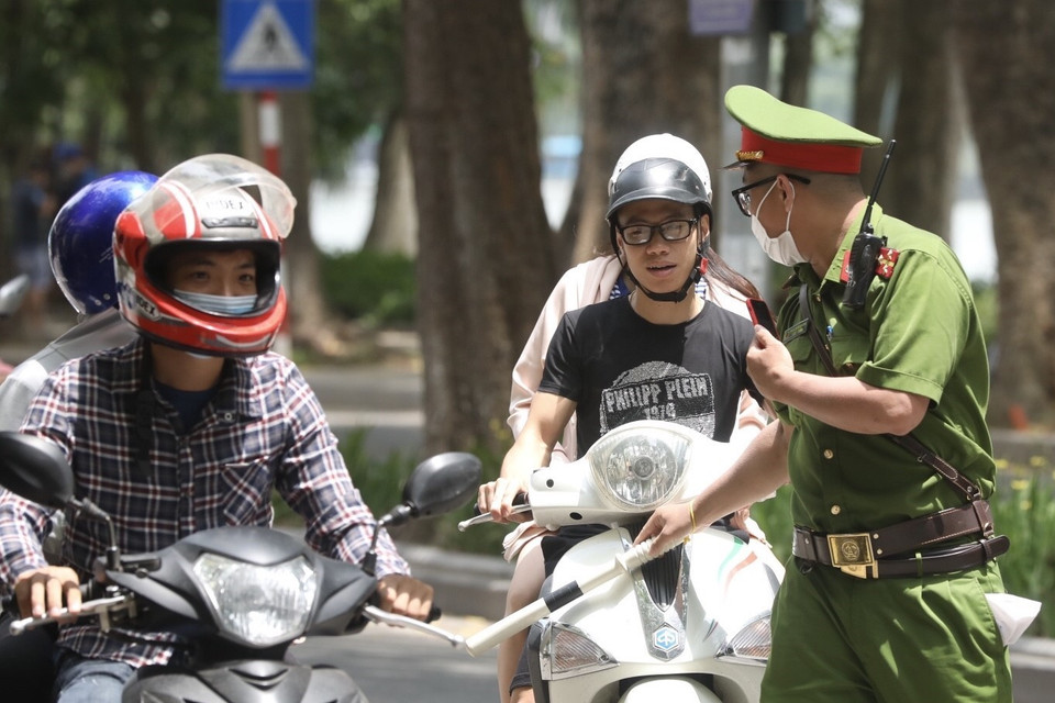 Lực lượng chức năng nhắc nhở, xử lý các trường hợp không đeo khẩu trang nơi công cộng. (Ảnh: Minh Quyết/TTXVN)