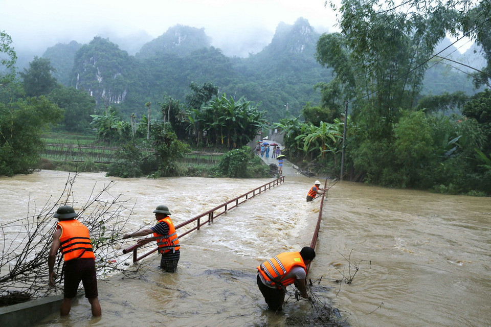 Lực lượng chức năng xã Mai Sao, huyện Chi Lăng vớt rác trôi, mắc vào lan can cầu dân sinh đi vào thôn Nà Lốc - vùng trồng na đặc sản theo quy trình VietGap của huyện Chi Lăng. (Ảnh: Phạm Hậu/TTXVN)