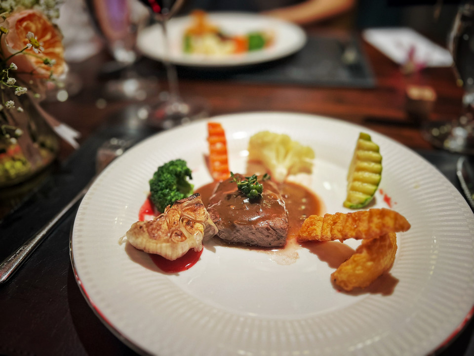 Bò nhập khẩu cao cấp nướng sốt tiêu đen với tỏi nướng, hành, khoai tây và rau xanh. (Ảnh: Mai Mai/Vietnam+)