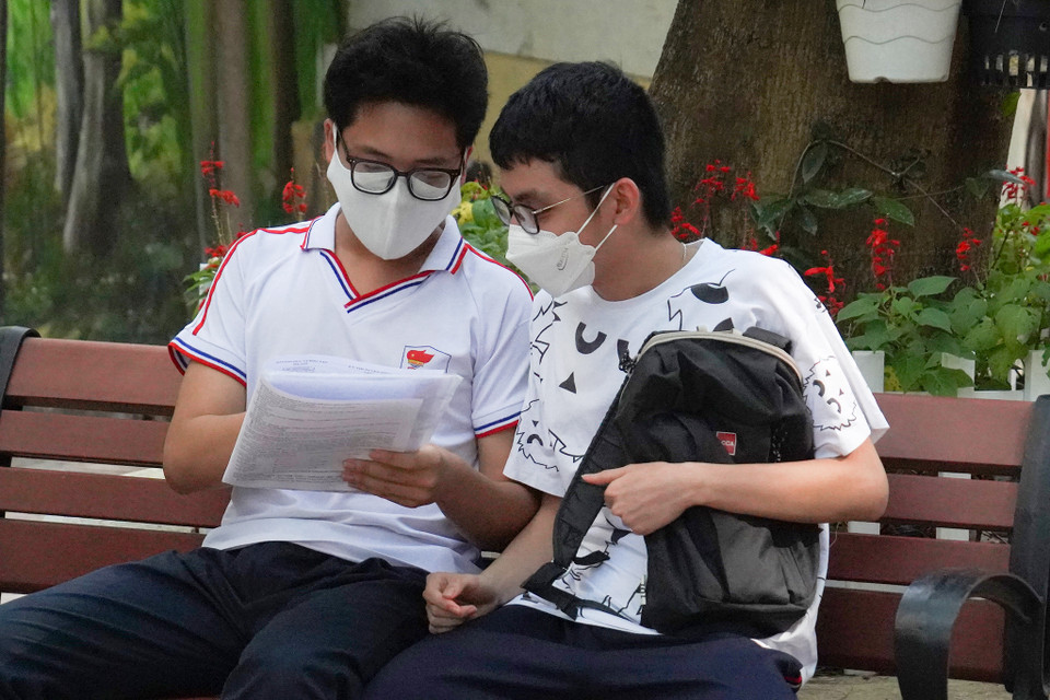 Một số sỹ tử nán lại điểm thi để trao đổi về kết quả bài thi môn Toán. (Ảnh: PV/Vietnam+)