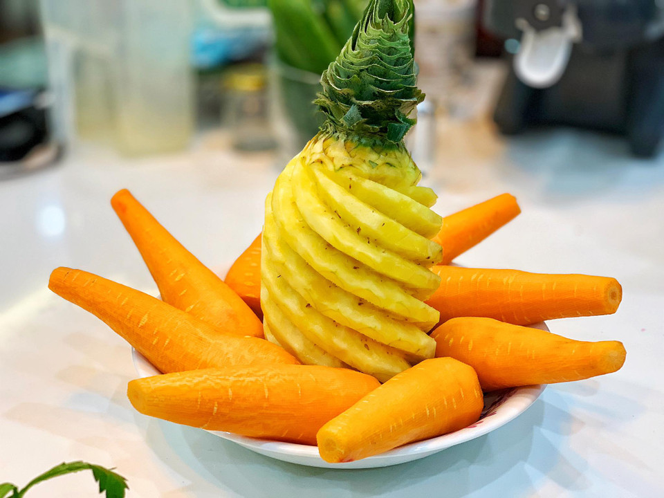 Trong nước ép các loại rau củ, trái cây, cà rốt và dứa được ví như nguyên liệu nền và sẽ chiếm khoảng 60-70% tổng nguyên liệu. Cà rốt có tác dụng bổ mắt, đẹp da, thải độc. Dứa giàu vitamin, enzyme và chất chống oxy hóa. Loại quả nhiệt đới này có thể cung cấp đầy đủ chất dinh dưỡng, vitamin và khoáng chất. Ngoài ra, dứa còn có tác dụng hỗ trợ tăng cường hệ thống miễn dịch, hỗ trợ điều trị chứng khó tiêu và giúp xương chắc khỏe. (Ảnh: Mai Mai/Vietnam+)