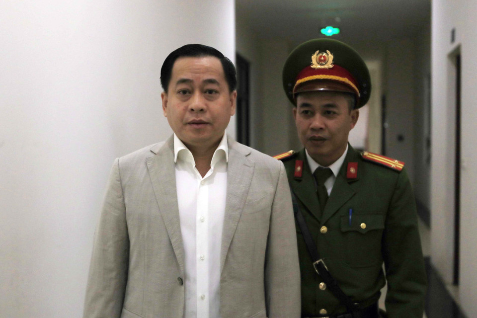 Cảnh sát dẫn giải bị cáo Phan Văn Anh Vũ (sinh năm 1975, Chủ tịch Hội đồng quản trị Công ty cổ phần Xây dựng 79, Công ty cổ phần Bắc Nam 79, Công ty trách nhiệm hữu hạn I.V.C, Công ty cổ phần đầu tư Nhất Gia Phúc) đến tòa xét xử. (Ảnh: Doãn Tấn/TTXVN)