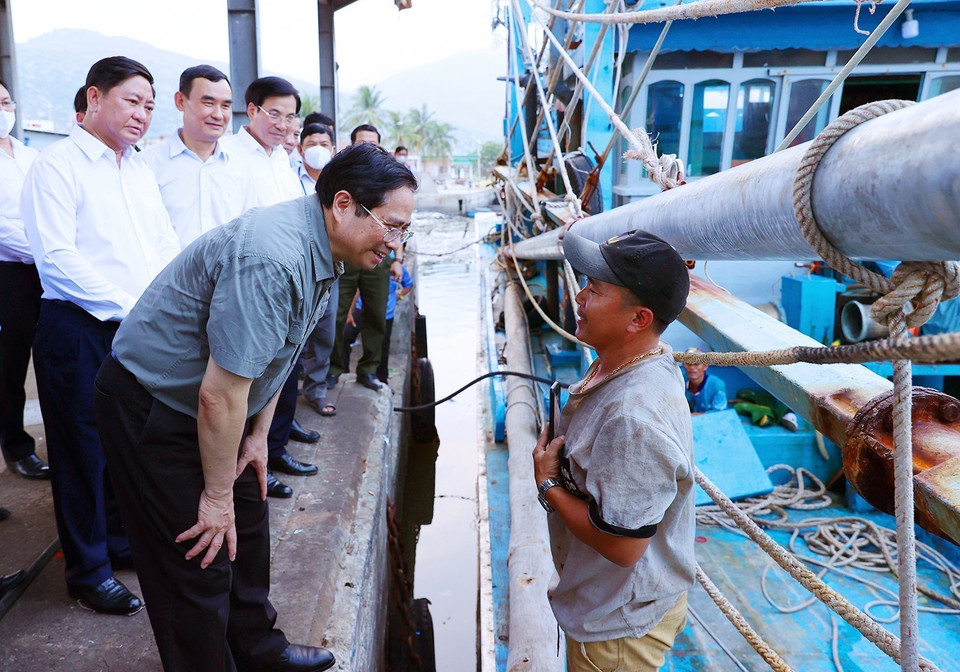 Thủ tướng Phạm Minh Chính thăm hỏi, động viên ngư dân tàu cá đang neo đậu tại cảng cá xã Cà Ná. (Ảnh: Dương Giang/TTXVN)