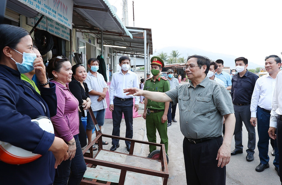 Thủ tướng Phạm Minh Chính thăm hỏi, động viên người dân tại cảng cá xã Cà Ná, huyện Thuận Nam. (Ảnh: Dương Giang/TTXVN)