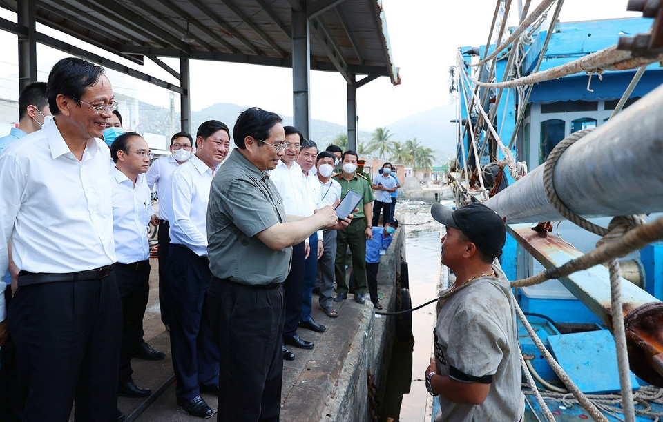 Thủ tướng Phạm Minh Chính thăm hỏi, động viên ngư dân tàu cá đang neo đậu tại cảng cá xã Cà Ná. (Ảnh: Dương Giang/TTXVN)