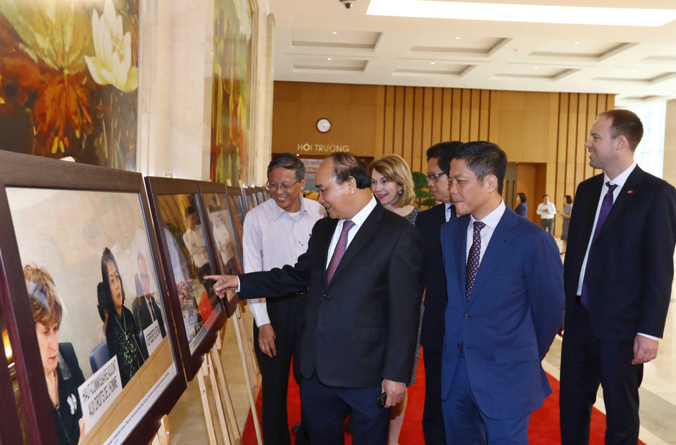 Thủ tướng Nguyễn Xuân Phúc, Trưởng Ban Chỉ đạo quốc gia về hội nhập quốc tế và các đại biểu tham quan trưng bày ảnh của TTXVN về hội nhập quốc tế. (Ảnh: Thống Nhất/TTXVN)