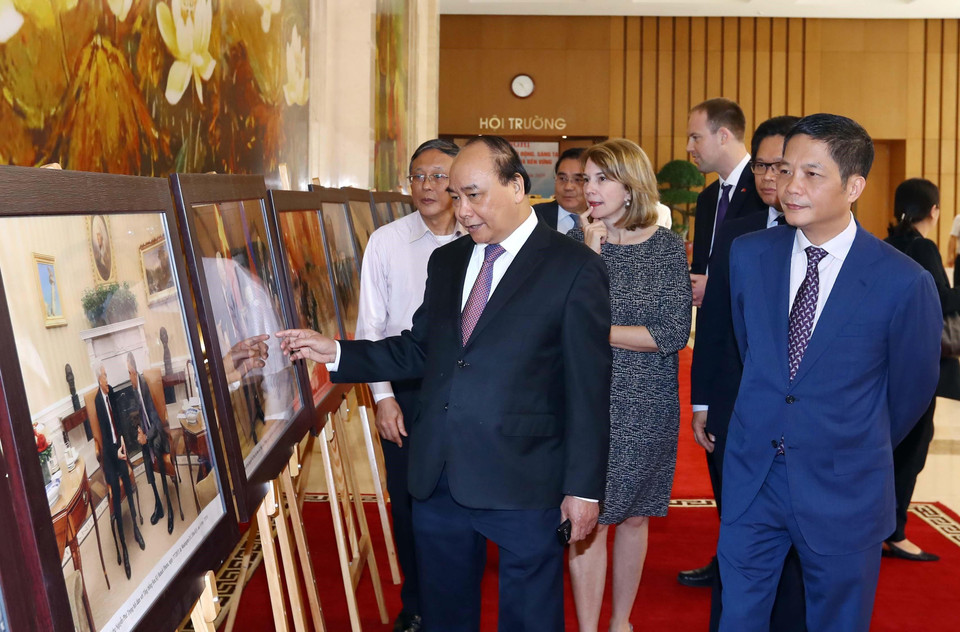 Thủ tướng Nguyễn Xuân Phúc, Trưởng Ban Chỉ đạo quốc gia về hội nhập quốc tế và các đại biểu tham quan trưng bày ảnh của TTXVN về hội nhập quốc tế. (Ảnh: Thống Nhất/TTXVN)