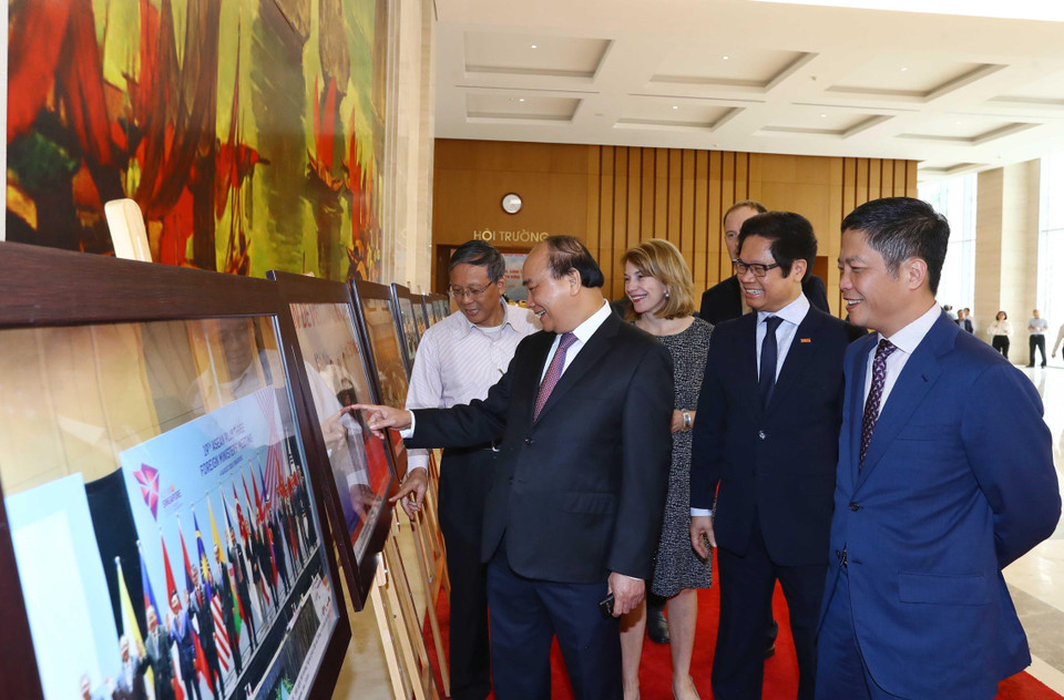 Thủ tướng Nguyễn Xuân Phúc, Trưởng Ban Chỉ đạo quốc gia về hội nhập quốc tế và các đại biểu tham quan trưng bày ảnh của TTXVN về hội nhập quốc tế. (Ảnh: Thống Nhất/TTXVN)