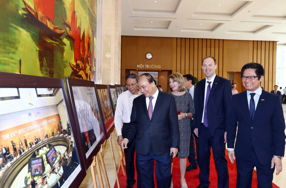 Thủ tướng Nguyễn Xuân Phúc, Trưởng Ban Chỉ đạo quốc gia về hội nhập quốc tế và các đại biểu tham quan trưng bày ảnh của TTXVN về hội nhập quốc tế. (Ảnh: Thống Nhất/TTXVN)