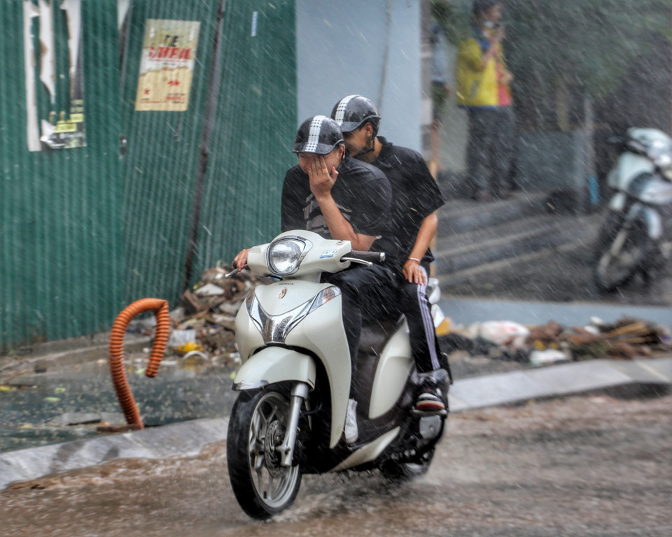 Mưa lớn đột ngột khiến một số người không kịp mặc áo mưa.(Ảnh: Tuấn Đức/TTXVN)