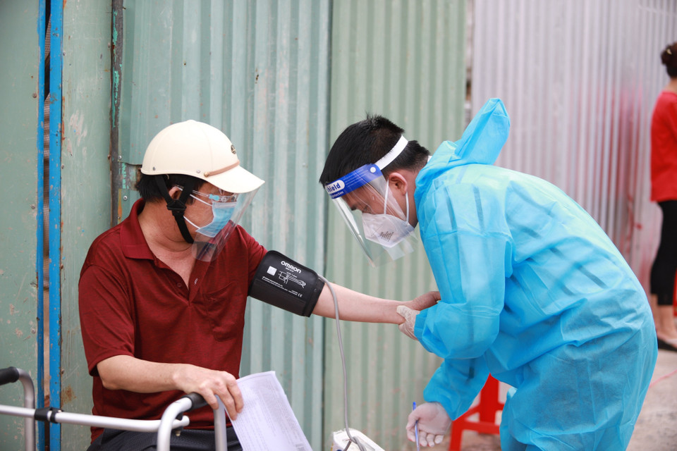 Nhân viên y tế đo huyết áp cho người dân trước khi thực hiện tiêm chủng tại điểm tiêm UBND phường 9 (quận Gò Vấp, Thành phố Hồ Chí Minh). (Ảnh: Thu Hương/TTXVN)