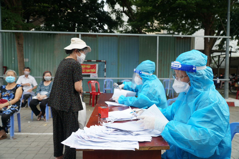 Nhân viên y tế hỗ trợ người dân tra cứu thông tin trước khi thực hiện tiêm chủng tại điểm tiêm UBND phường 9 (quận Gò Vấp, Thành phố Hồ Chí Minh). (Ảnh: Thu Hương/TTXVN)