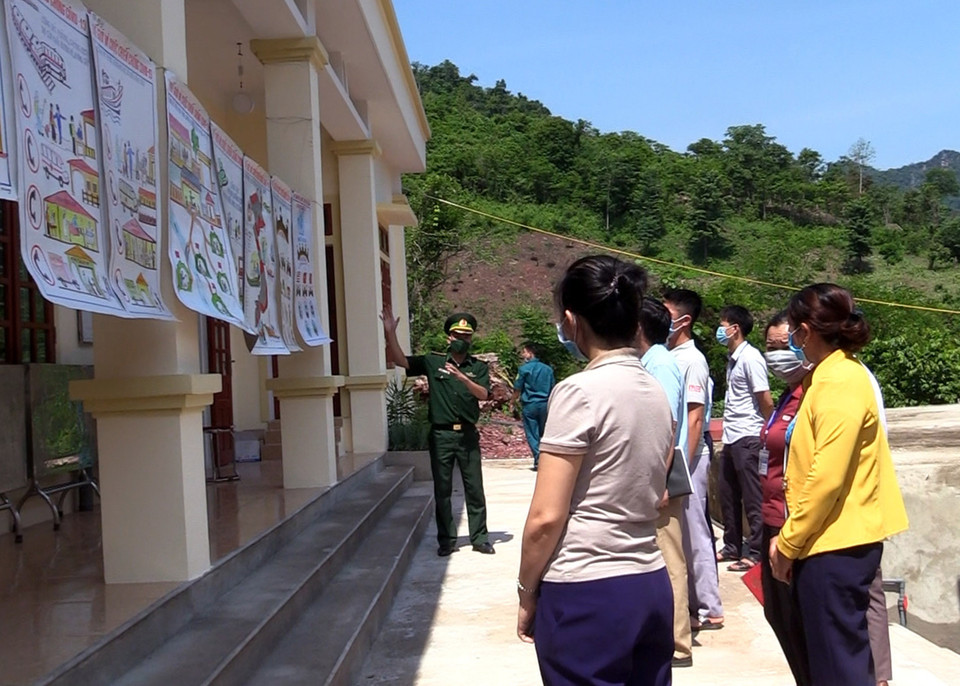 Các chiến sỹ Đồn biên phòng Mỹ Lý, Bộ Chỉ huy Bộ đội Biên phòng tỉnh Nghệ An, tuyên truyền về dịch COVID-19 bằng tranh cổ động cho nhân dân xã Mỹ Lý, huyện Kỳ Sơn. (Ảnh: Văn Tý/TTXVN)