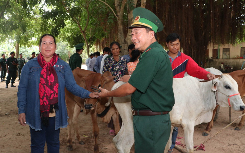 Đại tá Phạm Văn Phong, Chính ủy Bộ đội Biên phòng tỉnh An Giang (bìa phải) trao tặng bò giống cho các hộ nông dân nghèo tỉnh Kandal, Campuchia. (Ảnh: Công Mạo/TTXVN)