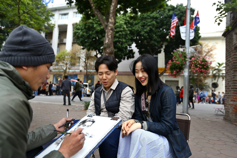 Nhiều du khách quốc tế thích thú vẽ chân dung tại khu vực hồ Hoàn Kiếm. (Ảnh: Minh Quyết/TTXVN)