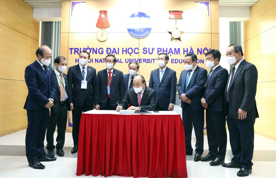 Chủ tịch nước Nguyễn Xuân Phúc viết cảm tưởng vào Sổ lưu niệm tại Phòng truyền thống của nhà trường. (Ảnh: Phạm Kiên/TTXVN)