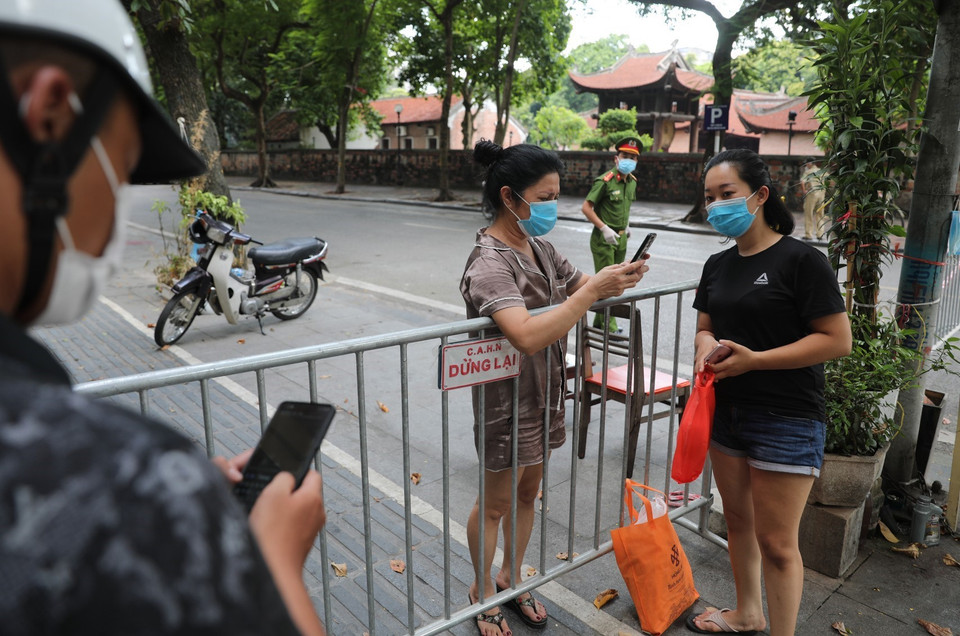 Người dân tiếp tế đồ vào cho người thân tại khu vực phố Quốc Tử Giám. (Ảnh: Thành Đạt/TTXVN)