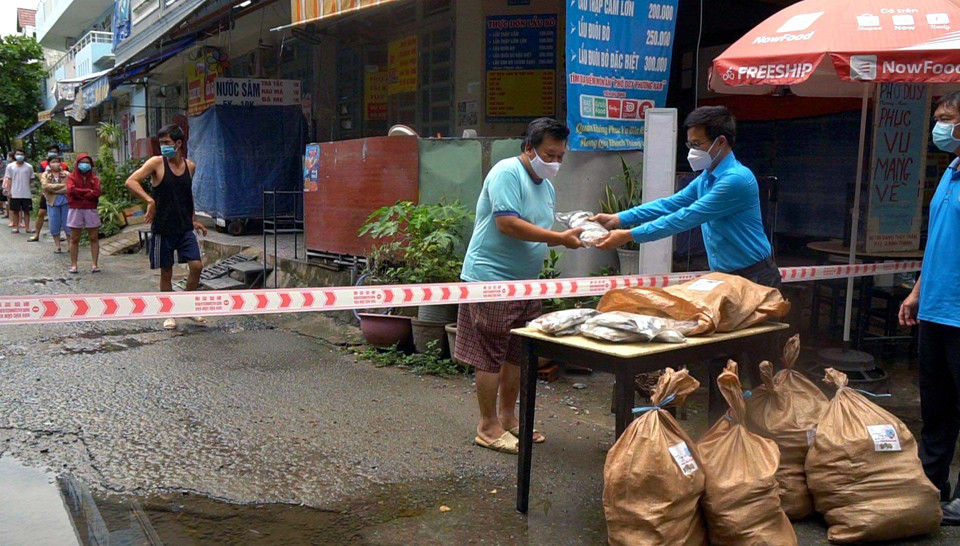 Đại diện Liên đoàn Lao động quận Bình Thạnh trao quà cho công nhân ở trọ, người nghèo trong khu phong tỏa. (Ảnh: TTXVN phát)