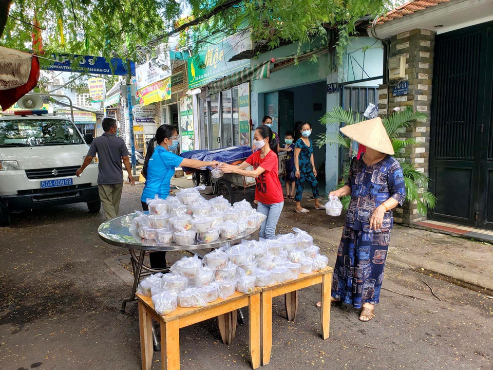 Đại diện Liên đoàn Lao động quận Gò Vấp trao suất ăn nghĩa tình cho công nhân ở trọ, người nghèo trong khu phong tỏa. (Ảnh: Thanh Vũ/TTXVN)